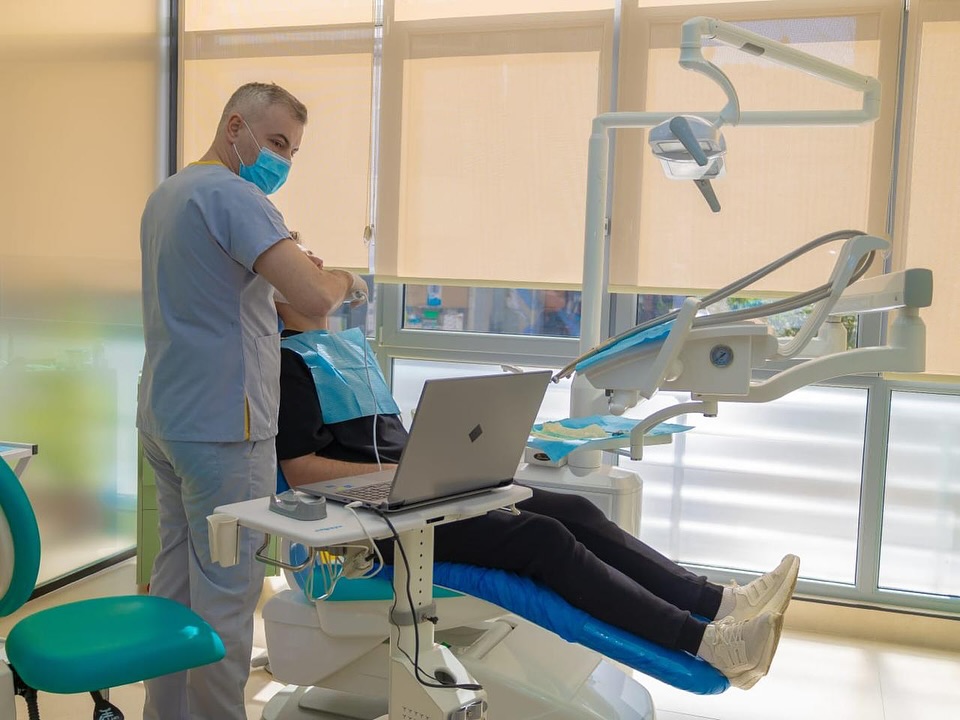 Dentista con paziente e laptop